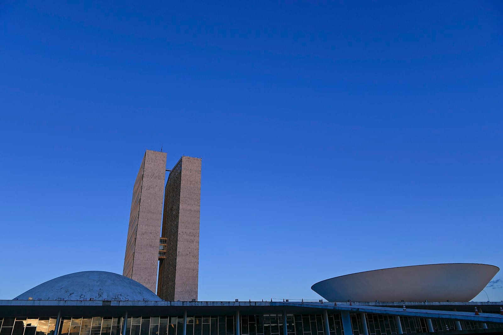 Palácio do Congresso Nacional, em Brasília, ao entardecer, com as duas torres entre a cúpula do Senado, à esquerda, e a da Câmara, à direita